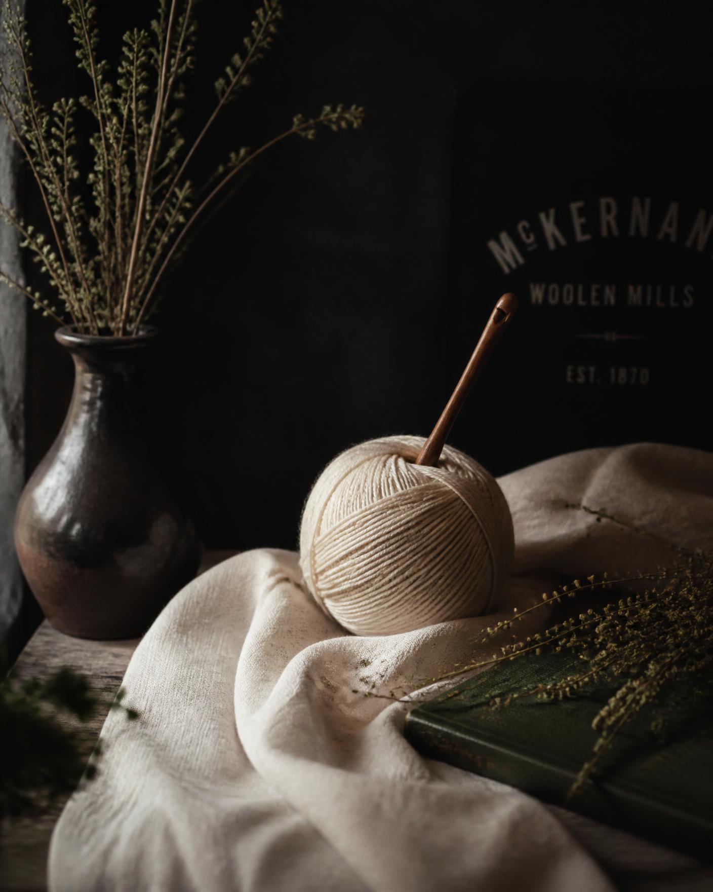 Ivory linen, natural wool and a wooden hook on a dark mercantile table